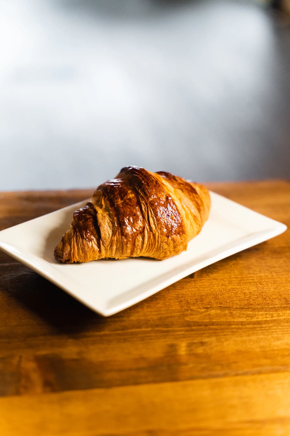 A golden pastry on a white plate on a wooden table